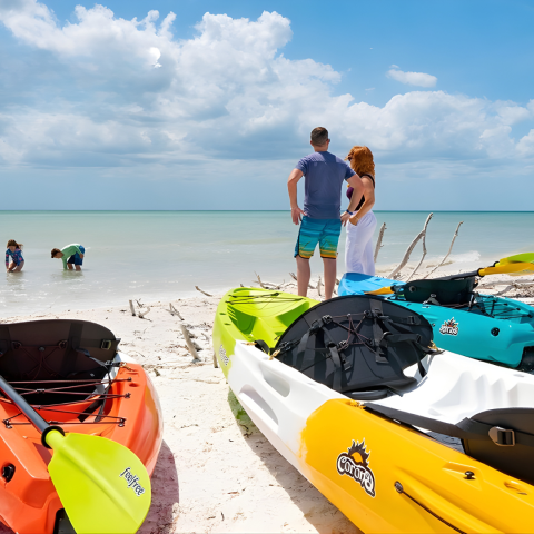 Couple on beach with colorful kayaks; children play in shallow water.