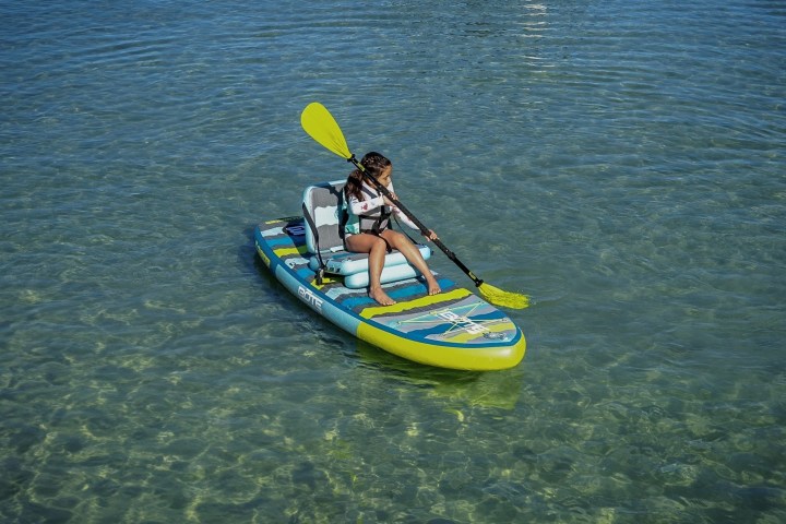 Person paddling on a stand-up paddleboard in clear, calm water.