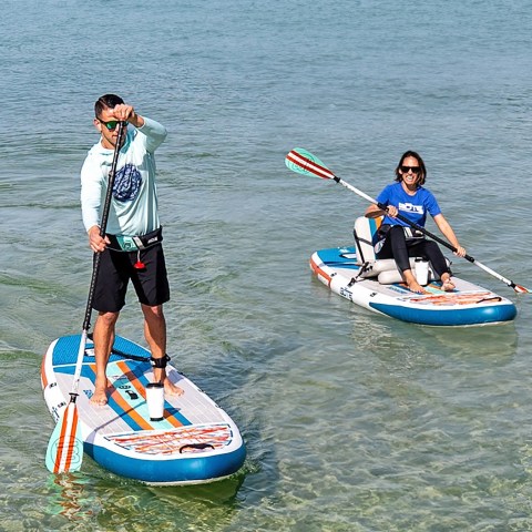 Two people paddleboarding on clear, shallow water.