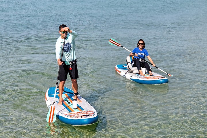 Two people paddleboarding on clear, shallow water.
