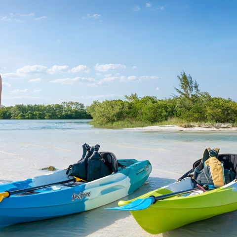 Couple walking on beach, two kayaks on sand, clear sky.